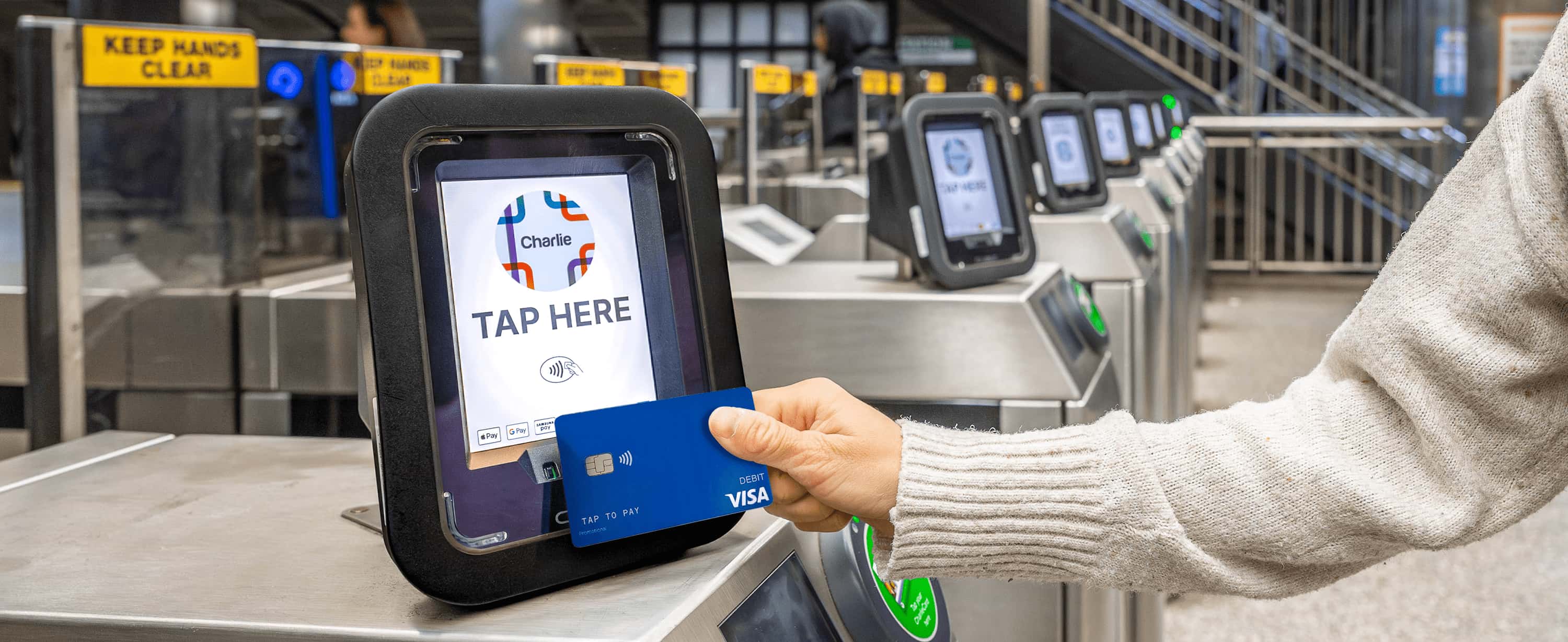 A customer taps a contactless credit card against a Charlie gate validator in a T station