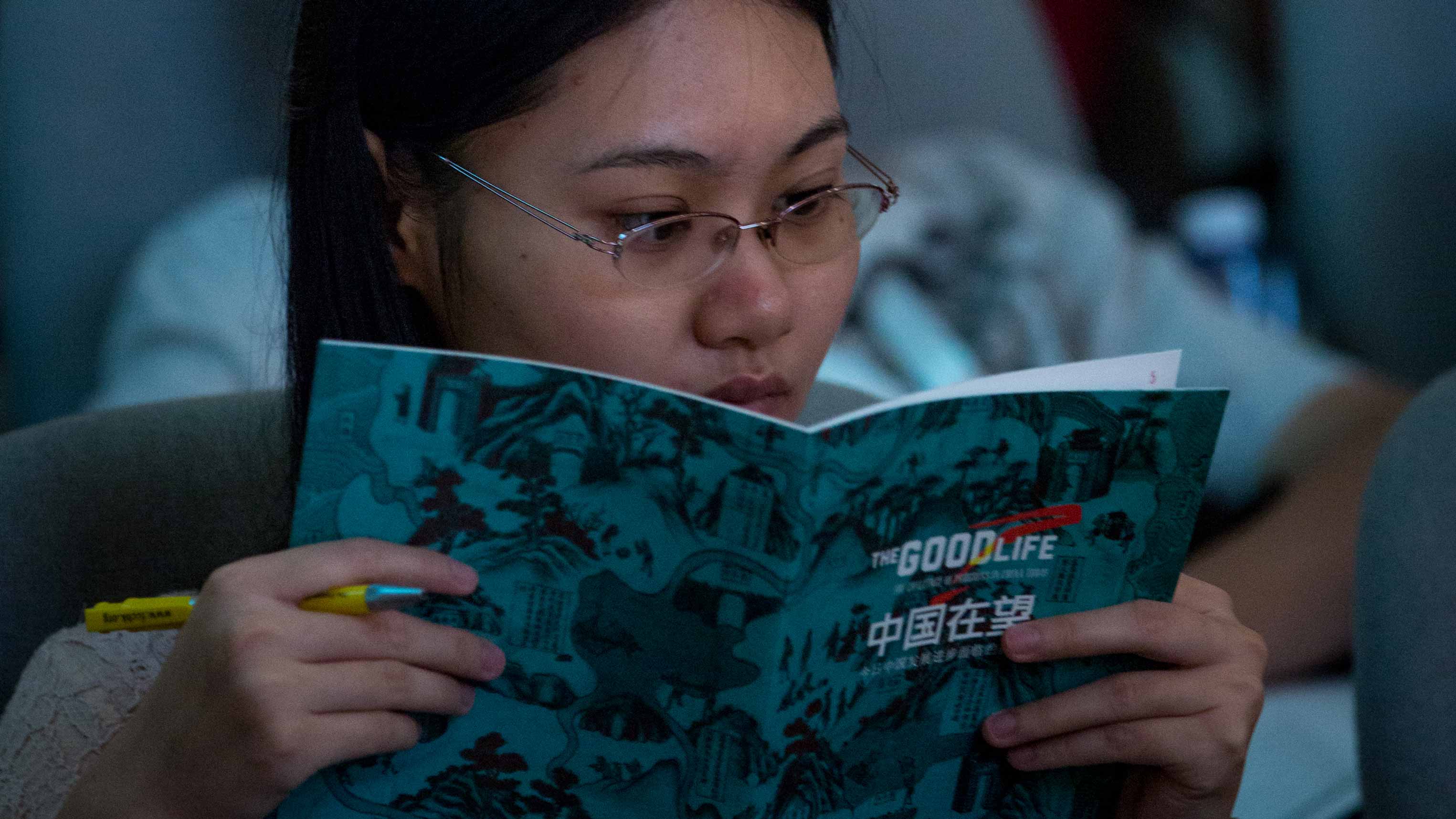 An attendee at The Good Life conference reads the conference program in the audience.